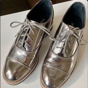 Silver Oxford style patent leather shoes.